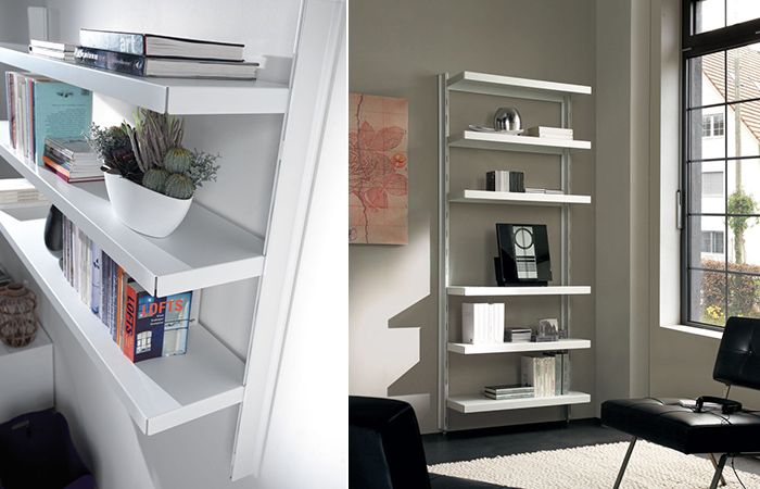 Libreria bianca moderna con scaffali aperti, decorata con libri, piante e oggetti, in una stanza ben illuminata.
