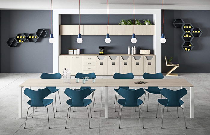 Sala da pranzo moderna con tavolo lungo, sedie blu, lampade a sospensione e scaffale con oggetti decorativi.